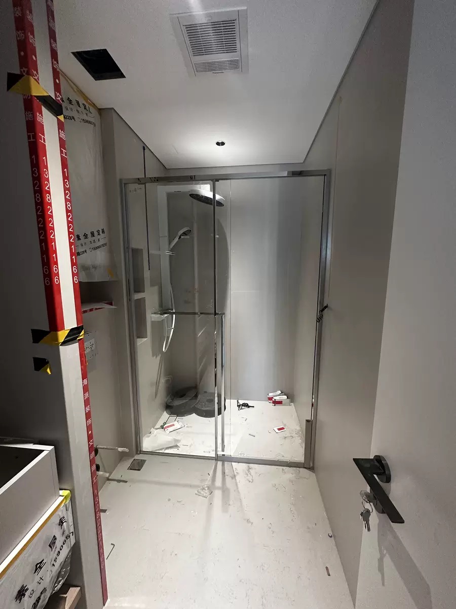 Clear glass shower enclosure installation in a marble bathroom